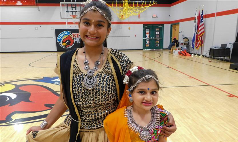 Two girls stand closely together in a school gym